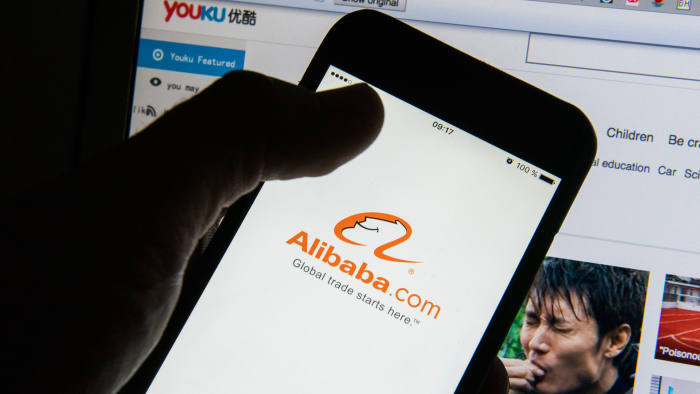 The Alibaba Group Holding Ltd. app logo is displayed on an Apple Inc. iPhone 6 smartphone screen is held in front of the Youku Tudou Inc. website in this arranged photograph in Hong Kong, China, on Saturday, Oct. 17, 2015. Alibaba offered to buy the rest of Youku Tudou as billionaire Jack Ma seeks to stream more video content to Chinese Internet users through control of the YouTube-like site. Photographer: Xaume Olleros/Bloomberg
