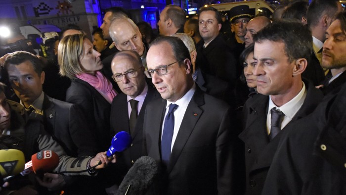 French President Francois Hollande (C), flanked by French Interior Minister Bernard Cazeneuve (Rear L) and French Prime Minister manuel Valls (R) addresses reporters near the Bataclan concert hall in central Paris, early on November 14, 2015. A number of people were killed in an &quot;unprecedented&quot; series of bombings and shootings across Paris and at the Stade de France stadium on November 13, and the death toll looked likely to rise as sources said dozens had been killed at the Bataclan popular music venue. AFP PHOTO / MIGUEL MEDINA