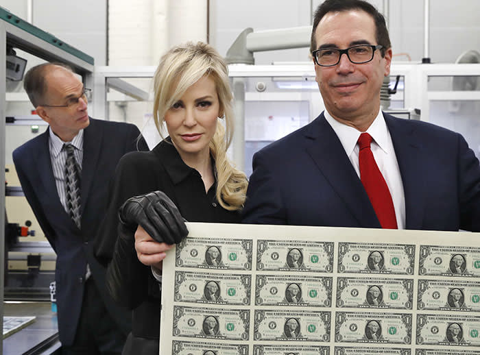 Treasury Secretary Steven Mnuchin, right, and his wife Louise Linton, hold up a sheet of new $1 bills, the first currency notes bearing his and U.S. Treasurer Jovita Carranza's signatures, Wednesday, Nov. 15, 2017, at the Bureau of Engraving and Printing (BEP) in Washington. The Mnuchin-Carranza notes, which are a new series of 2017, 50-subject $1 notes, will be sent to the Federal Reserve to issue into circulation. At left is BEP Director Leonard Olijar. (AP Photo/Jacquelyn Martin)