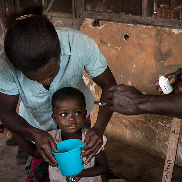 A child receives onchocerciasis medication from a volunteer distributor in Ghana
