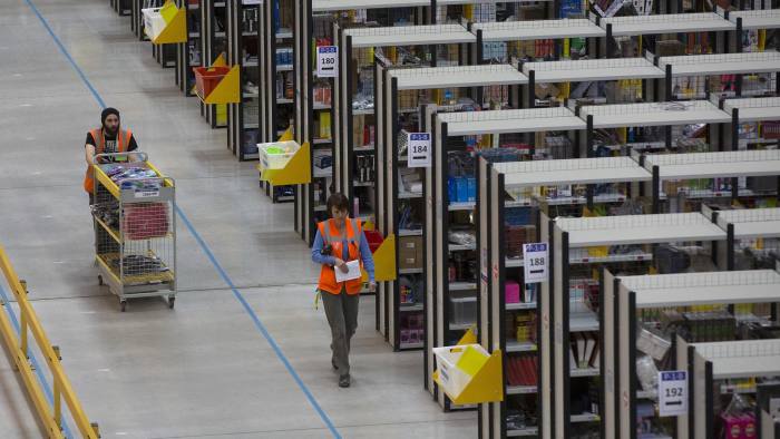 An employee pushes a cart as he processes customer orders ahead of shipping at one of Amazon.com Inc.'s fulfillment centers in Rugeley, U.K., on Monday, Dec. 2, 2013. Online retailers in the U.K. are anticipating their busiest day as shoppers flush with end-of-month pay-checks seek Christmas deals on the Web. Photographer: Simon Dawson/Bloomberg