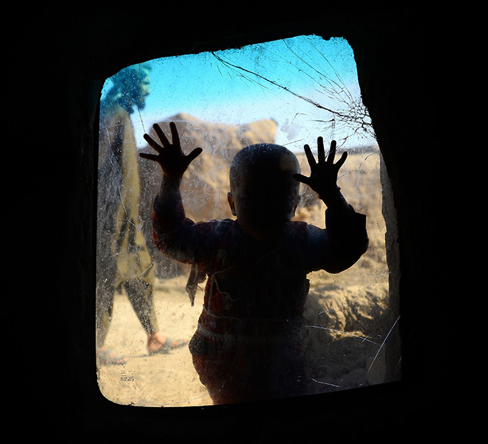 TOPSHOT - In this photograph taken on May 21, 2018 an internally displaced Afghan child looks on from a windows in her temporary home at a refugee camp on the outskirts of Herat. / AFP PHOTO / HOSHANG HASHIMIHOSHANG HASHIMI/AFP/Getty Images