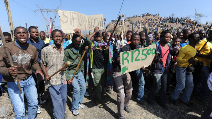 Miners demonstrate at a mountain close to the mine near Rustenburg where they are demanding that their wages are more than tripled on August 16, 2012. Clashes broke out over the weekend between members of the upstart Association of Mineworkers and Construction Union (AMCU) and the powerful National Union of Mineworkers (NUM). AFP PHOTO (Photo credit should read -/AFP/GettyImages)