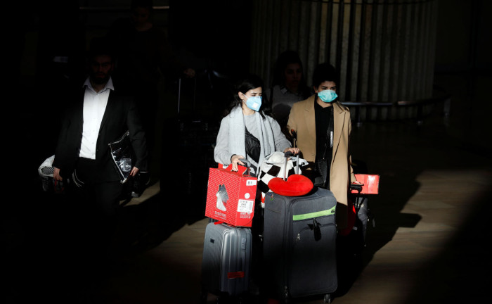 Travellers pull their suitcases while wearing masks in a terminal at Ben Gurion International airport in Lod, near Tel Aviv, Israel February 27, 2020. REUTERS/Amir Cohen
