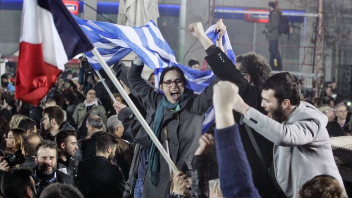 ATHENS, GREECE - JANUARY 25: A supporter of Alexis Tsipras, leader of Syriza left-wing party, holds the Greek and French  flag during a rally outside Athens University Headquarters January 25, 2015 in Athens, Greece. According to the latest opinion polls, the left-wing Syriza party are poised to defeat Prime Minister Antonis Samaras' conservative New Democracy party in the election, which has taken place today. European leaders fear that Greece could abandon the Euro, write off some of its national debt and put an end to the country's austerity by renegotiating the terms of its bailout if the radical Syriza party comes to power. Greece's potential withdrawal from the eurozone has become known as the 'Grexit'. (Photo by Milos Bicanski/Getty Images)