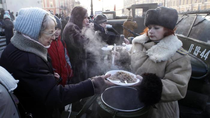 An enthusiast in historical uniform hands out portions of boiled buckwheat to passersby during a street event in St. Petersburg January 27, 2012. Russians on Friday marked the end of the 872 day siege of Leningrad in 1943 which claimed the lives of more than 500,000 people. REUTERS/Alexander Demianchuk (RUSSIA - Tags: SOCIETY ANNIVERSARY) - RTR2WXQB