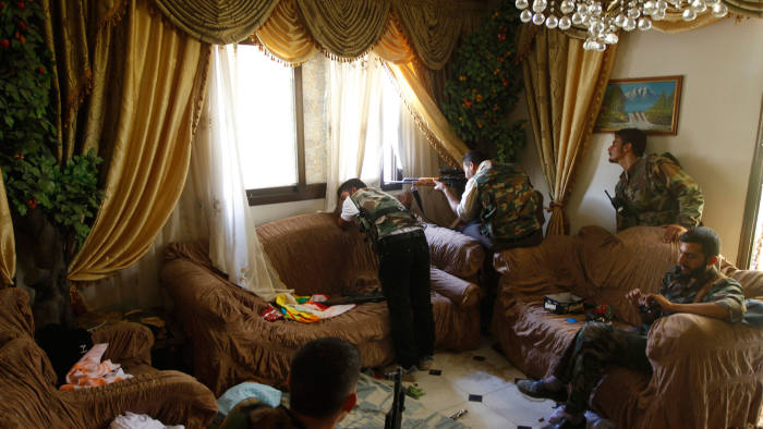 A Free Syrian Army fighter fires his rifle from a house in the city of Aleppo