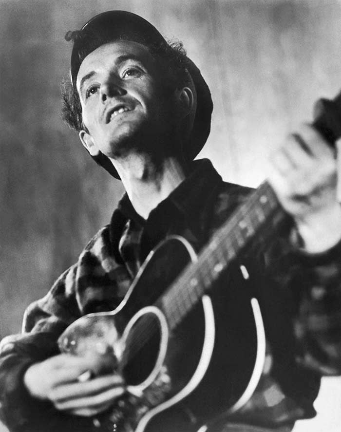 Waist-up photo of American folk singer and composer Woody Guthrie (1912-1967) playing his guitar. Ca. 1960s. (Photo by ÂÂ John Springer Collection/CORBIS/Corbis via Getty Images)