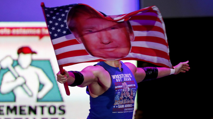 Wrestler Sam Polinsky aka Sam Adonis takes the ring at Arena Mexico waving an American flag emblazoned with a photo of U.S. President Donald Trump, in Mexico City, Sunday, Feb. 12, 2017. He's the guy Mexicans love to hate: The American pro wrestler has become a sensation in Mexico City by adopting the ring persona of a flamboyant Trump supporter. (AP Photo/Eduardo Verdugo)