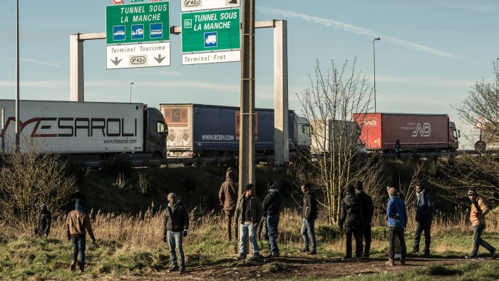 Migrants stand near the A16 motorway near the site of the Eurotunnel in Coquelles, near Calais, northern France on January 21, 2016. Approximately 300 migrants have tried to board trucks protected by French police, according to an estimate made by an AFP photographer present at the scene. Clashes already erupted briefly on the night of January 20 at the port bypass Calais between several hundred migrants and security forces, who fired tear gas to restore the situation, according to an AFP correspondent. These incidents occurred after the prefecture of Pas-de-Calais had set an ultimatum which expired early in the afternoon for the last migrants to leave a deforested 100 metre strip of the &quot;Jungle&quot; camp along the ring road for safety reasons. / AFP / PHILIPPE HUGUEN (Photo credit should read PHILIPPE HUGUEN/AFP/Getty Images)