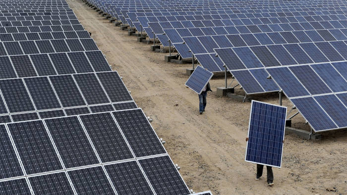 Employees carry solar panels at a solar power plant in Aksu, Xinjiang Uyghur Autonomous Region, in this May 18, 2012 file photo