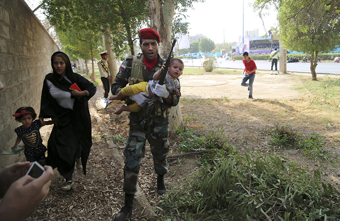 FILE - In this Saturday, Sept. 22, 2018 file photo provided by Mehr News Agency, an Iranian soldier carries a child away from a shooting during a military parade, in the southwestern city of Ahvaz, Iran. On Saturday, Arab separatists killed at least 25 people in an attack targeting the military parade in Iran, and President Donald Trump‚Äôs lawyer Rudy Giuliani declared that the Iranian government would be toppled. From Saturday‚Äôs attack in Ahvaz to America resuming sanctions despite Iran‚Äôs compliance with the 2015 nuclear deal, pressure on Tehran is rising and its leaders are growing more combative toward the West. (AP Photo/Mehr News Agency, Mehdi Pedramkhoo)