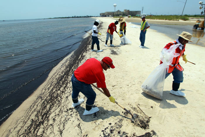 WAVELAND, MS - JULY 09: Workers clean up oily globs that washed ashore from the Deepwater Horizon oil spill in the Gulf of Mexico July 9, 2010 in Waveland, Mississippi. Millions of gallons of oil have spilled into the Gulf since the April 20 explosion on the drilling platform. (Photo by Joe Raedle/Getty Images)