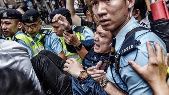 Pro-independence activist Wayne Chan is removed by police from a location outside the Foreign Correspondents' Club (FCC), as people protest ahead of a speech by pro-independence activist Andy Chan, in Hong Kong on August 14, 2018. - Rival protesters gathered outside Hong Kong's Foreign Correspondents' Club on August 14 as it was set to host a talk by an independence activist, despite a request by Beijing to cancel. (Photo by Philip FONG / AFP) (Photo credit should read PHILIP FONG/AFP/Getty Images)