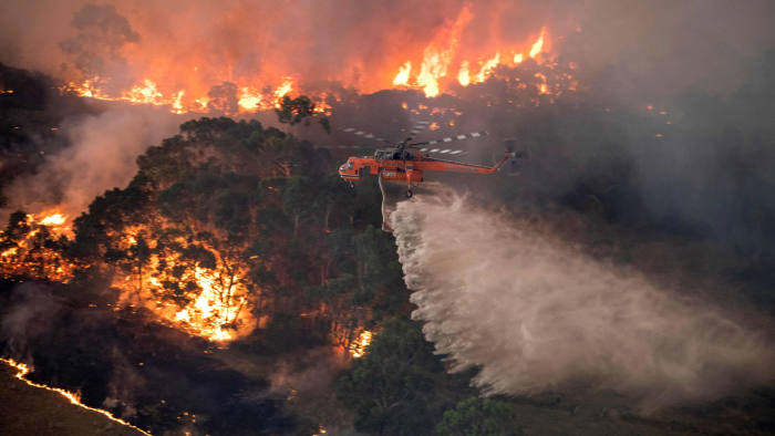 A handout photo taken and received on December 31, 2019 from the State Government of Victoria shows a helicopter fighting a bushfire near Bairnsdale in Victoria's East Gippsland region. - Thousands of holidaymakers and locals were forced to flee to beaches in fire-ravaged southeast Australia on December 31, as blazes ripped through popular tourist areas leaving no escape by land. (Photo by Handout / STATE GOVERNMENT OF VICTORIA / AFP) / RESTRICTED TO EDITORIAL USE - MANDATORY CREDIT "AFP PHOTO / STATE GOVERNMENT OF VICTORIA" - NO MARKETING NO ADVERTISING CAMPAIGNS - DISTRIBUTED AS A SERVICE TO CLIENTS (Photo by HANDOUT/STATE GOVERNMENT OF VICTORIA/AFP via Getty Images)