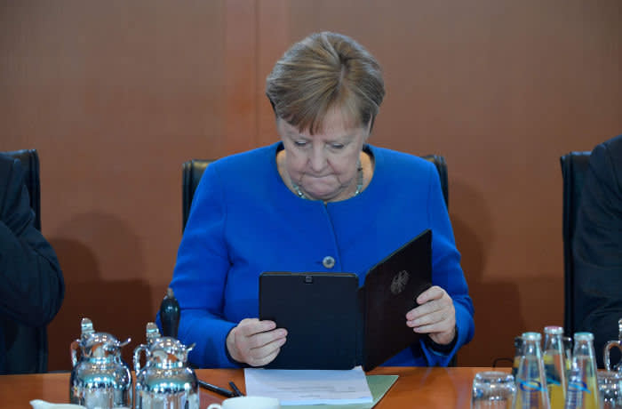 TOPSHOT - German Chancellor Angela Merkel reads on her mobile device as she has taken seat to lead the weekly cabinet meeting on March 11, 2020 at the Chancellery in Berlin. (Photo by Tobias SCHWARZ / AFP) (Photo by TOBIAS SCHWARZ/AFP via Getty Images)