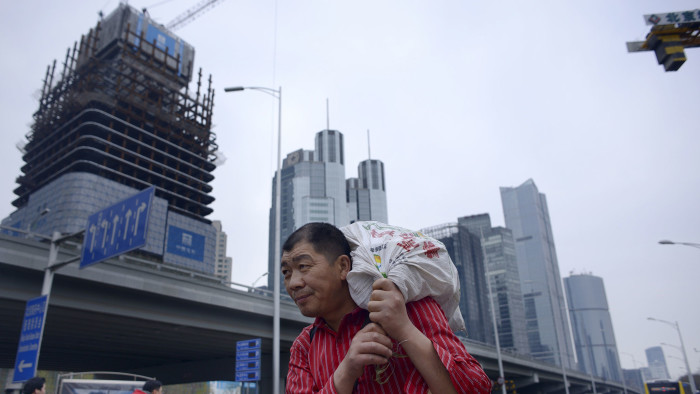 A man carries a package as he walks along a street at in Beijing's central business district