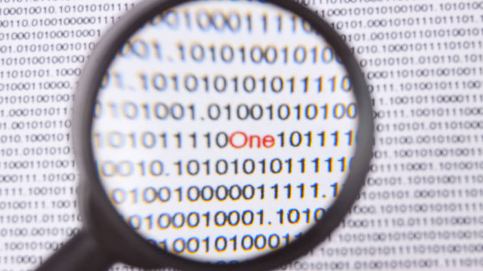 Magnifying glass showing binary numbers on a computer screen