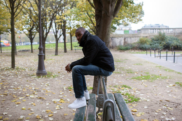 Abd Al Malik sitting on a bench in a Parisian park