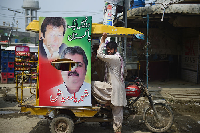 In this picture taken on July 16, 2018, a Pakistani driver looks on as a poster of Pakistani cricketer-turned-politician and head of the Pakistan Tehreek-i-Insaf (PTI) Imran Khan is seen on his rickshaw in Rawalpindi, ahead of the upcoming general elections. Pakistan goes to the polls on July 25 for tense nationwide elections marked by deadly attacks and accusations of military interference that could undermine their legitimacy. / AFP PHOTO / FAROOQ NAEEM / To go with 'PAKISTAN-ELECTION-MILITARY-POLITICS,ADVANCER' by David STOUTFAROOQ NAEEM/AFP/Getty Images