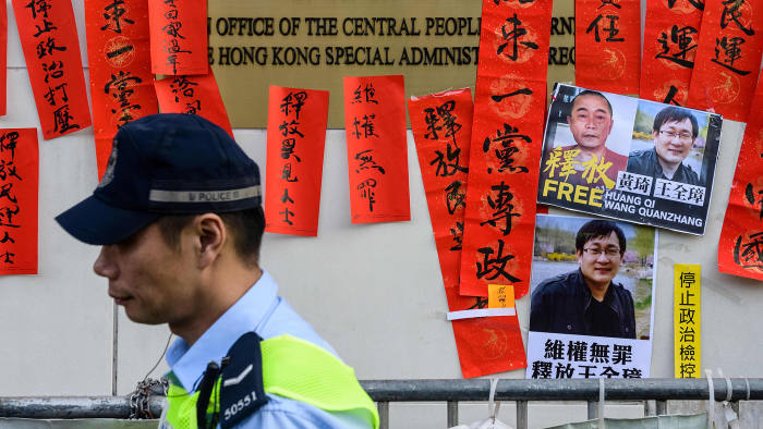 Police walk past messages in support of jailed Chinese human rights lawyer Wang Quanzhang (pictured R on placard) and China's first "cyber-dissident" and founder of human rights website "64 Tianwang", Huang Qi (pictured L on placard), after a protest attended by Hong Kong pro-democracy activists outside the Chinese Liaison Office in Hong Kong on January 29, 2019. - Prominent Chinese human rights lawyer Wang Quanzhang was sentenced on January 28 to four and a half years in prison for state subversion, sealing the fate of another attorney swept up in a 2015 crackdown. (Photo by Anthony WALLACE / AFP) (Photo credit should read ANTHONY WALLACE/AFP/Getty Images)