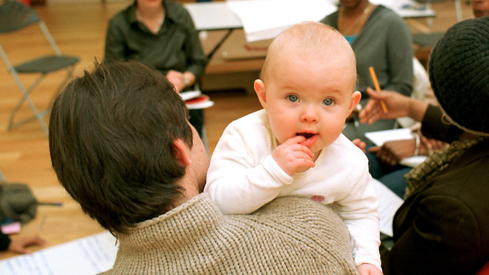 A toddler is held by his father during a Sure Start meeting organised by the Paddington Development Trust (PDT) for local parents in Queen's Park, North Paddington, London.