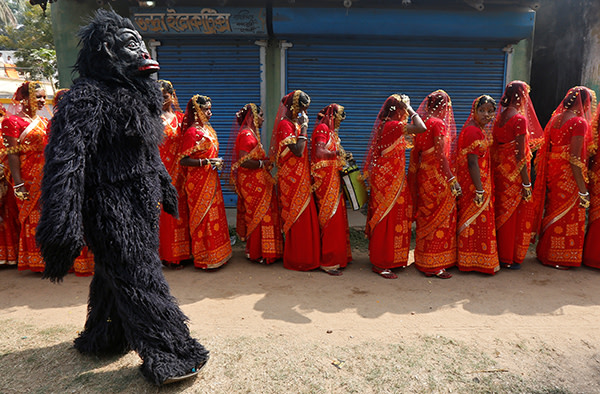 A performer dressed in a chimpanzee costume walks past brides as they arrive at a mass marriage ceremony in which, according to its organizers, 109 tribal, Muslim and Hindu couples from various villages across the state took their wedding vows, at Bahirkhand village, north of Kolkata, India February 5, 2017. REUTERS/Rupak De Chowdhuri TPX IMAGES OF THE DAY - RTX2ZOU5