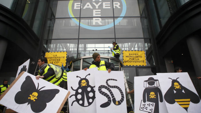 French activists of Attac stand in front of the Paris headquarters of Bayer AG to protest its production of environment-damaging pesticides in la Garenne Colombes, suburb of Paris, Thursday, March 14, 2019. Germany-based Bayer is also under fire from environmental activists in Europe and the U.S. for production of weed killer Roundup by its subsidiary Monsanto. Roundup's key ingredient glyphosate has been blamed for health problems including cancer. (AP Photo/Francois Mori)