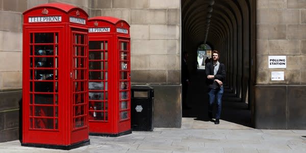 A pedestrian walks past red public telephone boxes near the Town Hall polling station in the European Union (EU) referendum in Manchester, U.K., on Thursday, June 23, 2016. Britain began voting Thursday on whether to remain a member of the European Union or split from the 28-nation bloc, a once-in-a-generation decision that will determine the U.K.'s future economic prosperity and the course of the EU. Photographer: Simon Dawson/Bloomberg