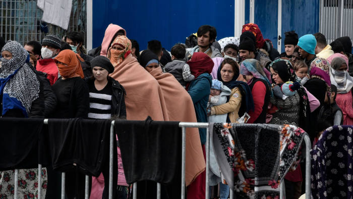 Migrants and refugess who arrived from Turkey to the island of Lesbos queue for food at the port of Mytilene where they camp, while waiting to board a Navy carrier on the island of Lesbos on March 5, 2020. (Photo by LOUISA GOULIAMAKI / AFP) (Photo by LOUISA GOULIAMAKI/AFP via Getty Images)