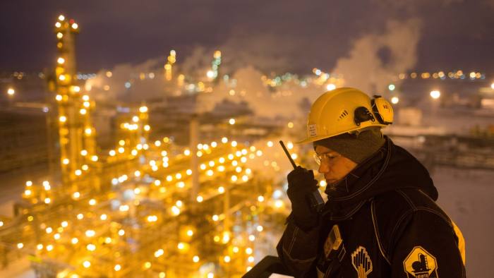 A worker holds a handheld transceiver as lights illuminate the low-temperature isomerization unit at the Novokuibyshevsk oil refinery plant, operated by Rosneft PJSC, in Novokuibyshevsk, Samara region, Russia, on Wednesday, Dec. 21, 2016. Oil trimmed a second weekly gain as investors weighed rising U.S. inventories against coming coordinated output cuts by OPEC and other producing nations. Photographer: Andrey Rudakov/Bloomberg