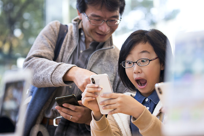 TOKYO, JAPAN - NOVEMBER 03: A girl reacts as she tries an iPhone X at the Apple Omotesando store on November 3, 2017 in Tokyo, Japan. Apple launched the latest iPhone featuring face recognition technology, a large 5.8-inch edge-to-edge high resolution OLED display and better front and back cameras with optical image stabilisation today. (Photo by Tomohiro Ohsumi/Getty Images)