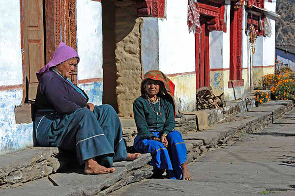 Villagers rest beside a traditional elongated house, or berklay
