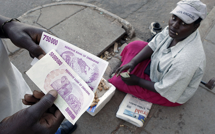 A Zimbabwean holds a newly issued fifty million dollar note at a street traders stand in the capital Harare April 4, 2008. The country is suffering a severe economic and political crisis with official inflation figures at over 100,000 per cent. The new note is worth the equivalent of three loaves of bread. REUTERS/Mike Hutchings (ZIMBABWE) - GM1E4441RJU01
