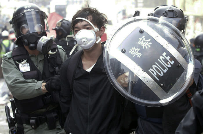Police officers detain a protester near the Hong Kong Polytechnic University in Hong Kong, Monday, Nov. 18, 2019. Hong Kong police have swooped in with tear gas and batons as protesters who have taken over a university campus make an apparent last-ditch effort to escape arrest. (AP Photo/Achmad Ibrahim)