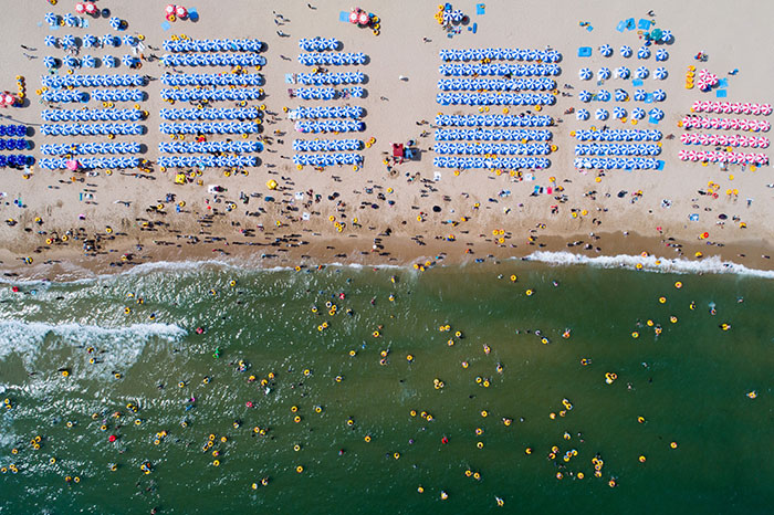 Bathers are seen on the beach and in the sea in this aerial photograph taken above Haeundae beach in Busan, South Korea, on Sunday, July 16, 2017. South Korea's minimum wage is set to increase next year by 16 percent to&nbsp;7,530 won ($6.60) per hour, the biggest jump since 2001, giving President&nbsp;Moon Jae-in&nbsp;an early victory in his push to boost incomes. Photographer: SeongJoon Cho/Bloomberg