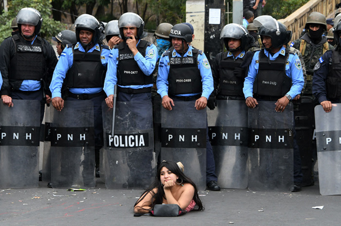 TOPSHOT - A supporter of the presidential candidate for the Honduran Opposition Alliance Against the Dictatorship for the past election, Salvador Nasralla, lies on the street in front of police officers during a demonstration against the contested re-election of President Juan Orlando Hernandez, in Tegucigalpa on January 21, 2018. The opposition called for a &quot;national strike&quot; on Saturday to focus on blocking the country's main roads ahead of the start of the president's new term in office on January 27. Dozens of people have been killed and hundreds jailed since Hernandez was declared the winner of the November 26 run-off election -- but only after a three week stretch of often-interrupted ballot counting that stoked tensions and sparked accusations of fraud in the Central American country. / AFP PHOTO / Orlando SIERRAORLANDO SIERRA/AFP/Getty Images