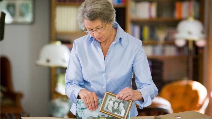 Senior woman packing picture frame in a cardboard box...D9HFYC Senior woman packing picture frame in a cardboard box