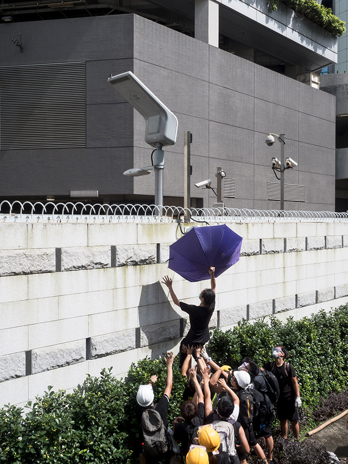 After protesters surround police headquarters in Wan Chai in late June, some attempted to block the CCTV cameras using an umbrella