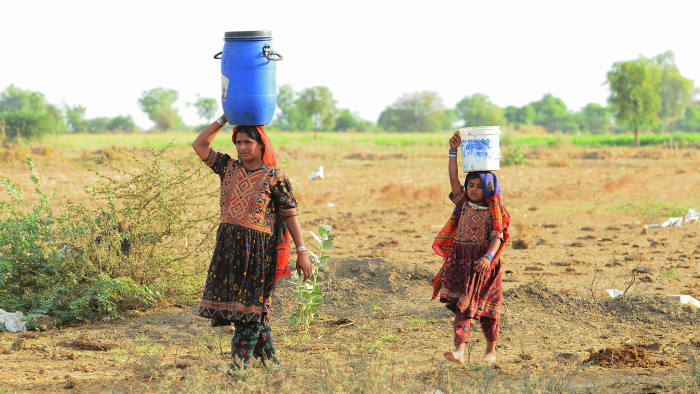 Migrant shepherds in Gujarat carry water to their camp