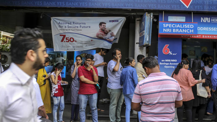 Customers stand in line outside a Yes Bank Ltd. branch in Mumbai, India, on Friday, March 6, 2020. India's stock and currency markets tumbled after the central bank seized control of beleaguered Yes Bank, raising concerns about the knock-on effects on the financial system. Photographer: Dhiraj Singh/Bloomberg