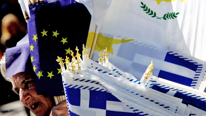 NICOSIA, CYPRUS - MARCH 25: A woman sells EU, Cypriot and Greek flags during a student parade marking Greece's Independence Day on March 25, 2013 in Nicosia, Cyprus. After days of negotiation, Eurozone finance ministers have agreed terms for a 10 billion euro bailout deal, which aims to prevent the collapse of Cypriot banks and ensure that Cyprus remain in the Eurozone. (