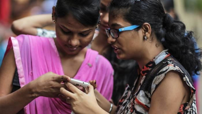 Students look at a Micromax Informatics Ltd. smartphone in Mumbai, India, on Saturday, Feb. 28, 2015. The government auction of telecom wireless spectrum starting March 4 is expected to raise as much as $15.6 billion from service providers including those controlled by billionaires Kumar Mangalam Birla, Sunil Mittal and Anil Ambani, according to ICRA Ltd. Photographer: Dhiraj Singh/Bloomberg