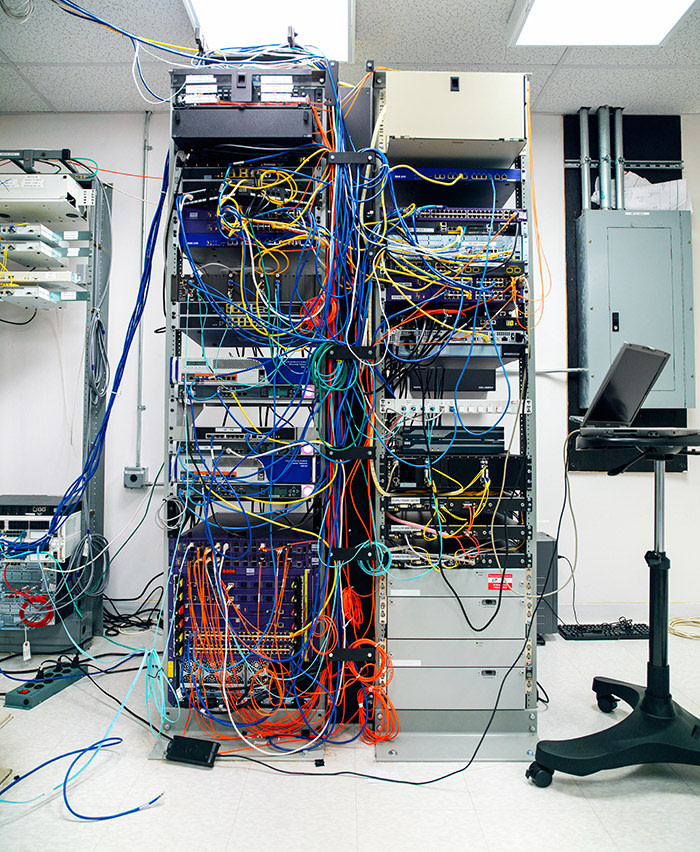 Unorganized server and network racks with tangled cables everywhere