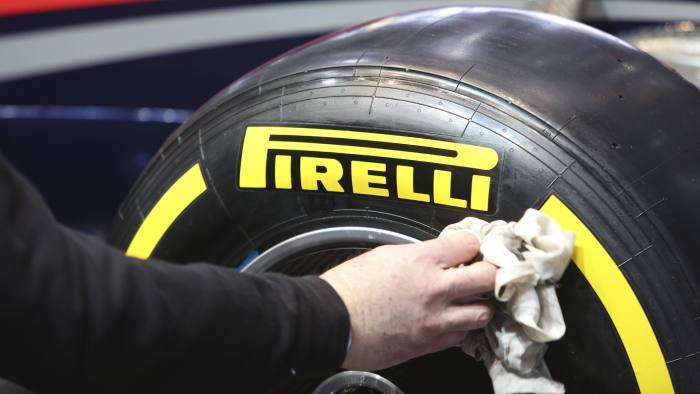 A worker cleans the wall of a Pirelli Formula One automobile tire, produced by Pirelli & C.SpA, on the company's stand ahead of the opening day of the 84th Geneva International Motor Show in Geneva, Switzerland, on Monday, March 3, 2014. The International Geneva Motor Show will run from Mar. 4, and showcase the latest models from the world's top automakers. Photographer: Chris Ratcliffe/Bloomberg