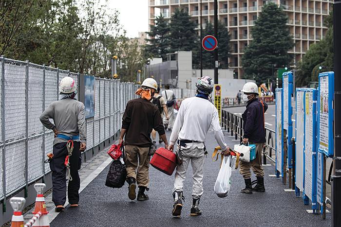 TOKYO, JAPAN - JULY 24: Construction workers walk near the New National Stadium, the main venue for the Tokyo 2020 Olympic and Paralympic Games, under construction on July 24, 2019 in Tokyo, Japan. (Photo by Tomohiro Ohsumi/Getty Images)