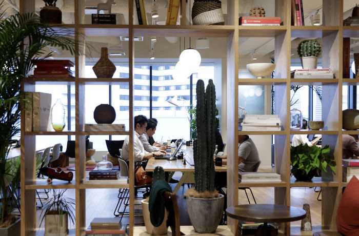 Members sit around a communal working table inside the WeWork Ocean Gate Minatomirai co-working office space, operated by The We Company, in Yokohama, Japan, on Friday, Oct. 11, 2019. WeWork formally withdrew the prospectus for an IPO this month, capping a botched fundraising effort that cost its top executive his job. The defeat places urgency on WeWork to find new sources of capital to keep its business running Photographer: Kiyoshi Ota/Bloomberg