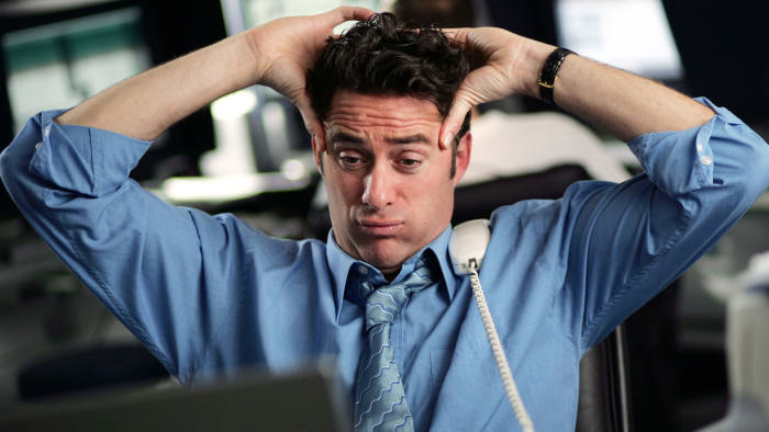 A business man with a phone rested on his shoulder, tired and frustrated