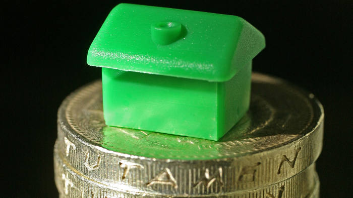 Houses from a Monopoly board game sit on top of British currency coins