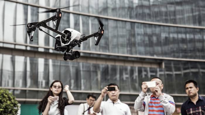 A DJI Inspire 1 Pro drone is flown during a demonstration at the SZ DJI Technology Co. headquarters as passersby look on in Shenzhen, China, on Wednesday, April 20, 2016. DJI, the world's largest maker of small civilian drones, said it's in discussions with Chinese government officials keen to gain access to the trove of data its airborne devices siphon up via its app.  Photographer: Qilai Shen/Bloomberg